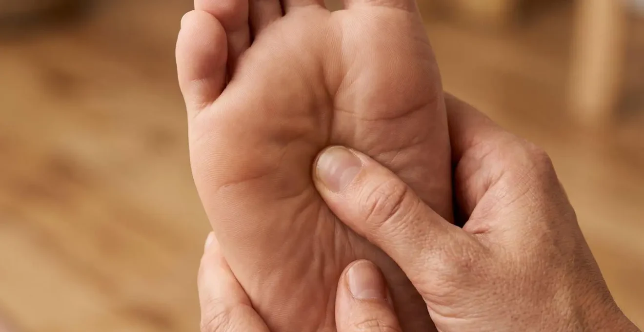 Gros plan sur des mains massant le point d'acupression sous la plante du pied
