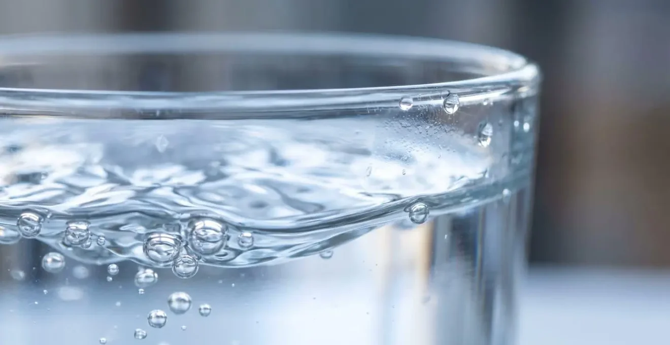 Vue macro d'un verre d'eau cristalline avec des reflets lumineux, symbolisant l'hydratation essentielle pour la santé du dos